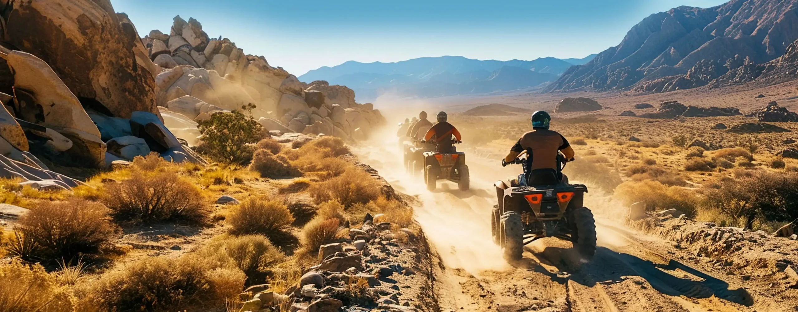 A group of ATVs ride through a desert.