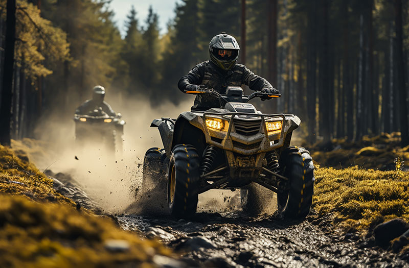 an image of two ATV riders on a muddy trail