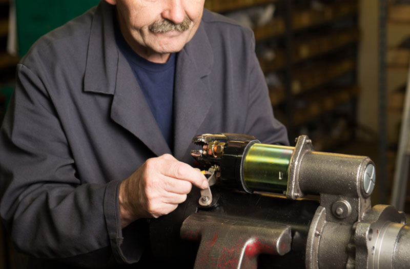 an image of a car technician working on a custom alternator and starter