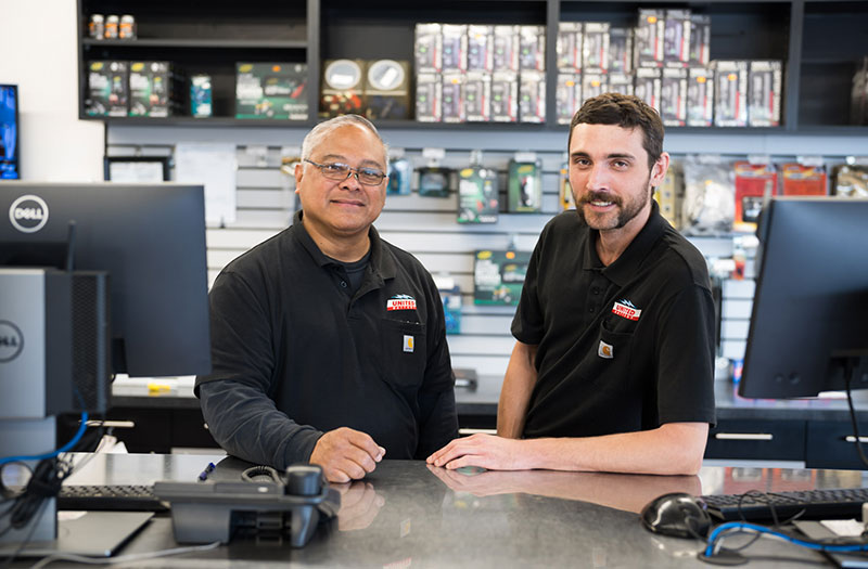 two United Battery employees smiling at the camera standing behind a counter