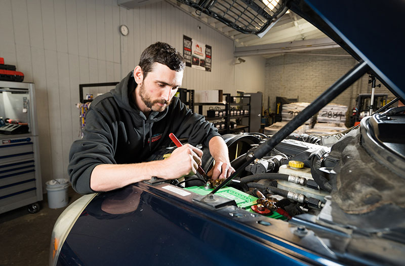 an image of a car technician working on an alternator