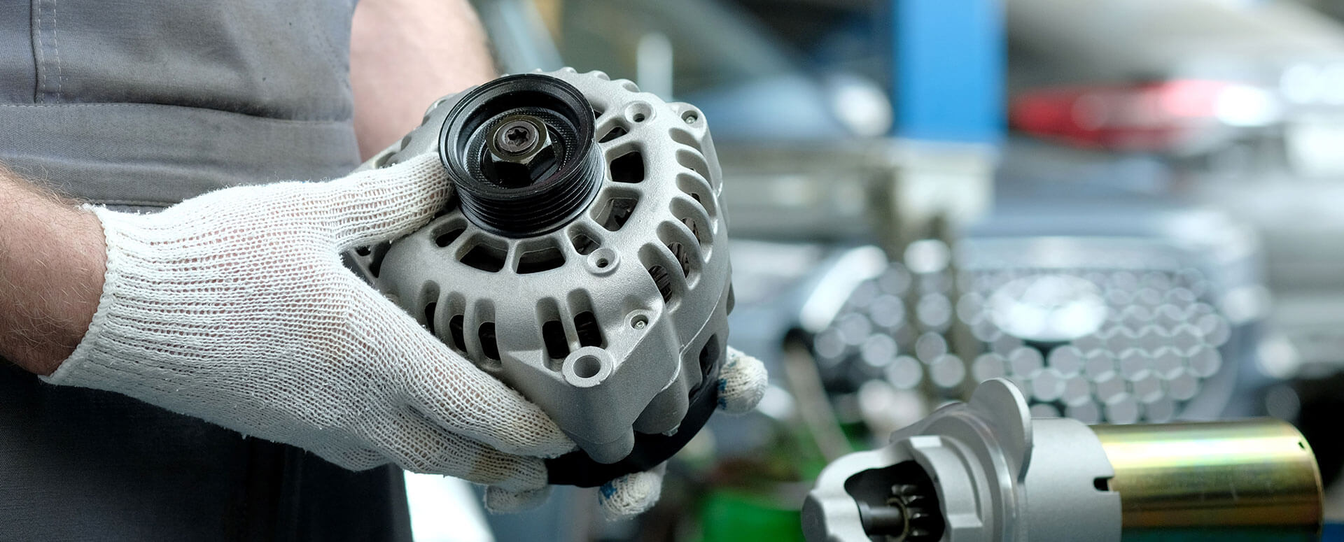 A technician holds a car alternator.
