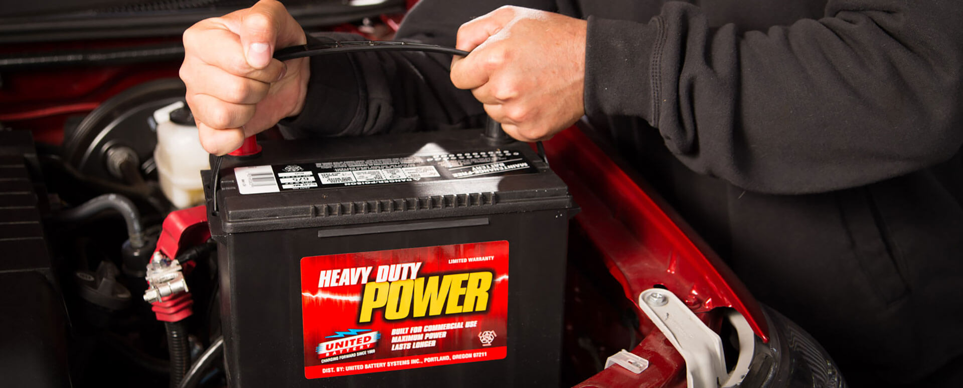 an image of a technician pulling a battery out of a car