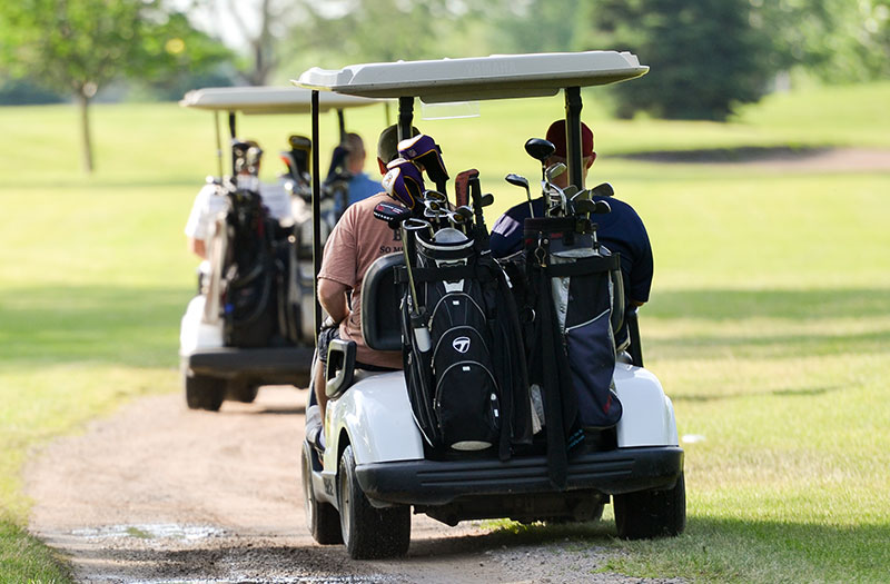 an image of a group of people driving two golf carts