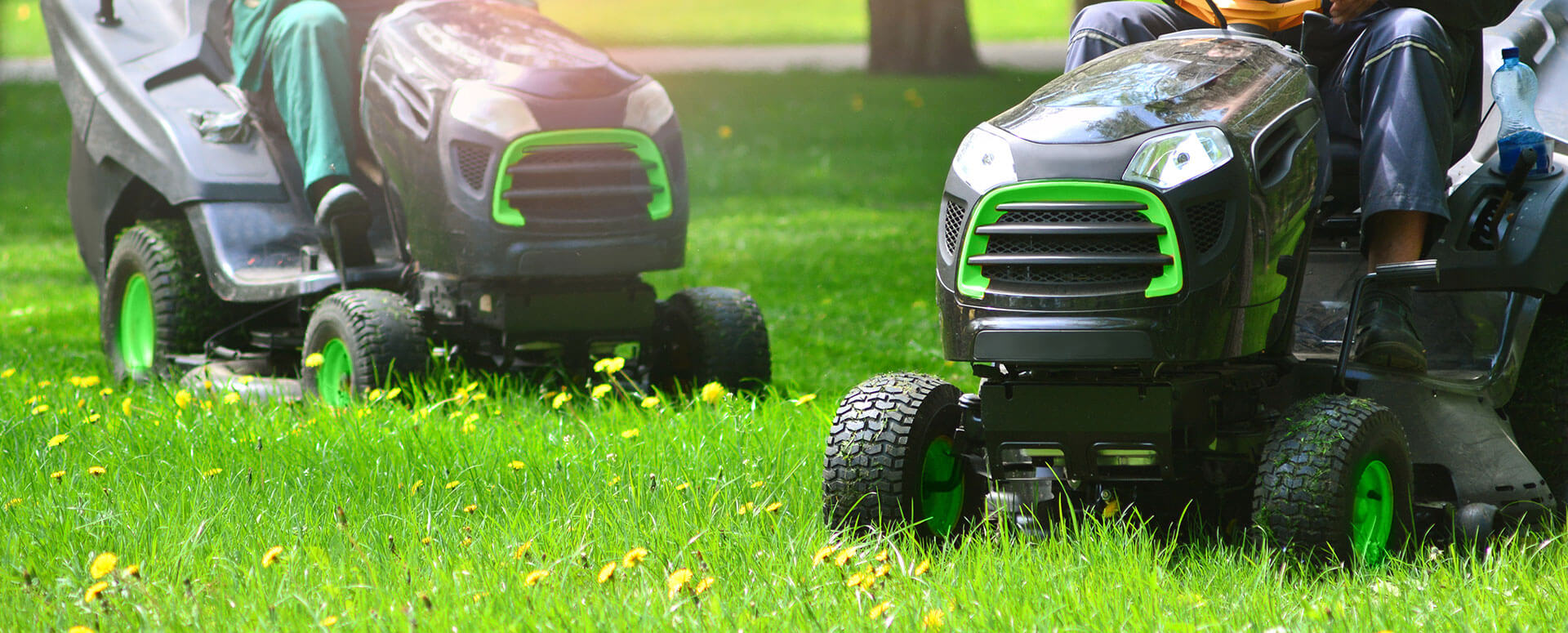 an image of two people using rideable lawn mowers