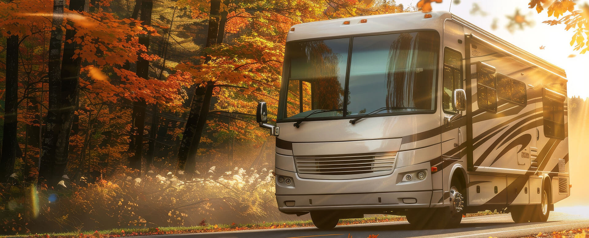 an image of an RV driving through the forest in Autumn with leaves in the air