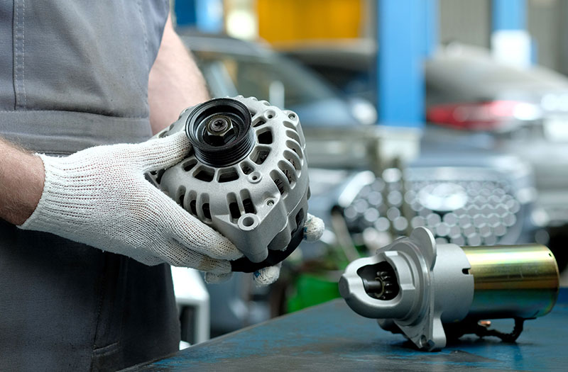 A technician examines a rebuilt alternator and starter.