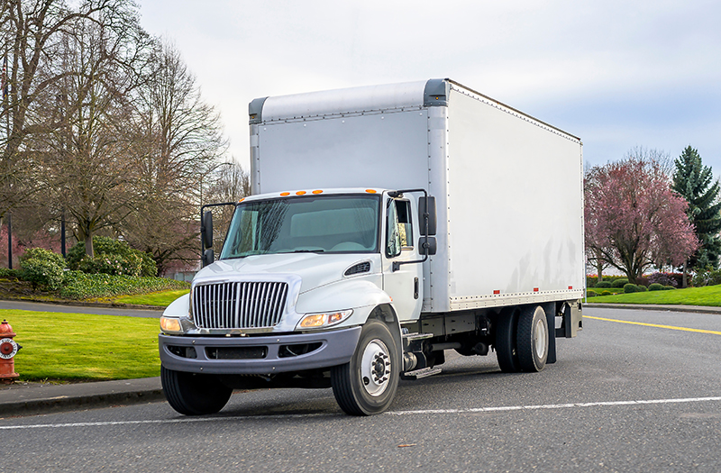 A box truck takes a turn down a street.