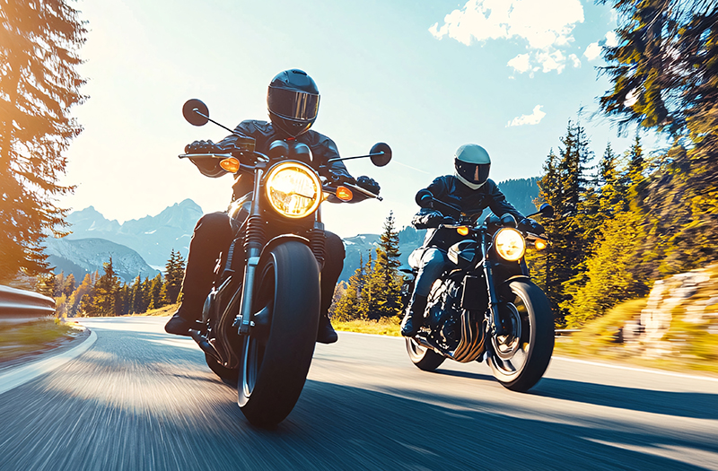 Two people riding motorcycles on a canyon road.